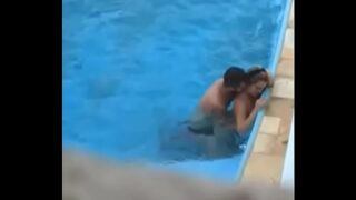 Chica sexy quitandose la ropa en piscina publica